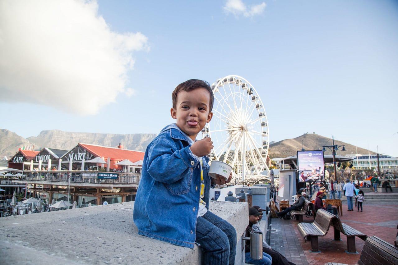 a boy sits in front of the Cape Wheel in Cape Town