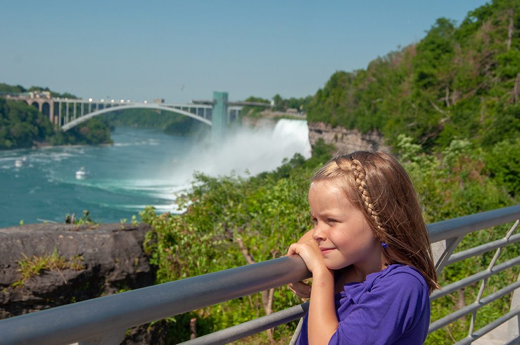 a girl is standing in font of Niagara Falls